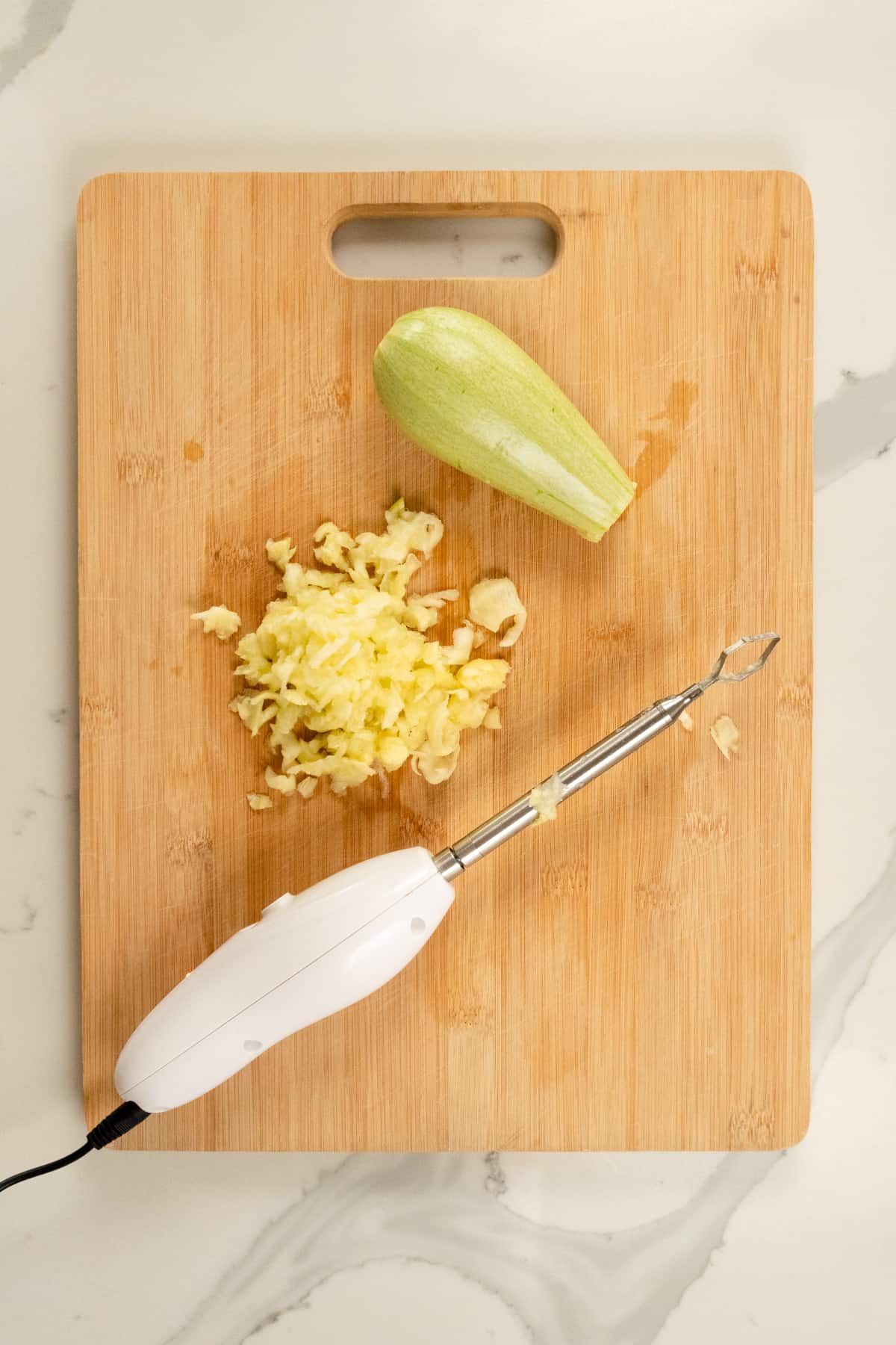 electric vegetable corer on a chopping board with a grey squash next to it