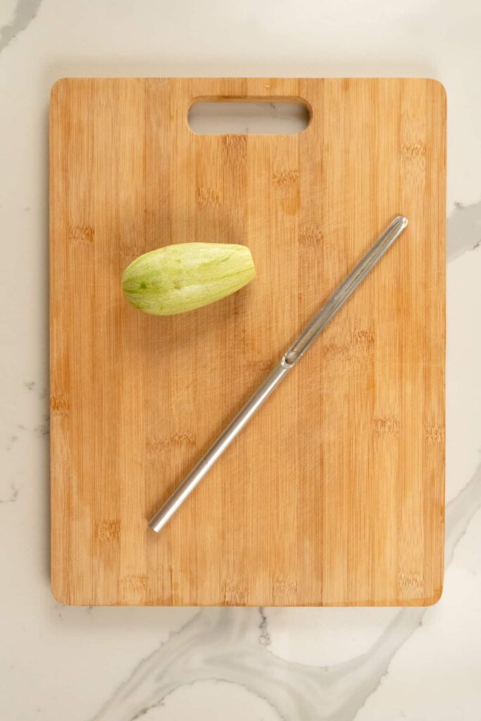 manual vegetable corer on a chopping board with a grey squash next to it