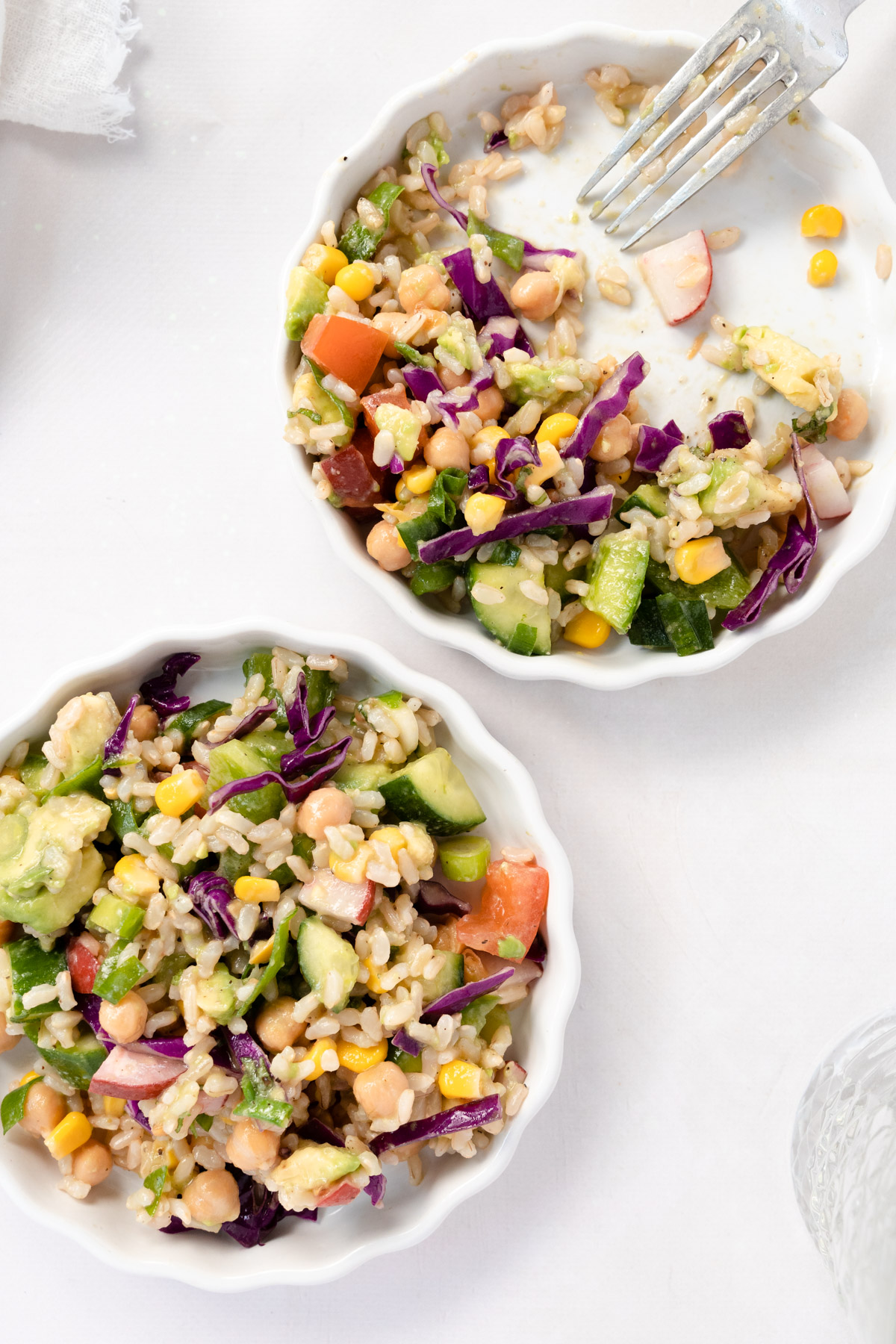 two white plates of brown rice salad