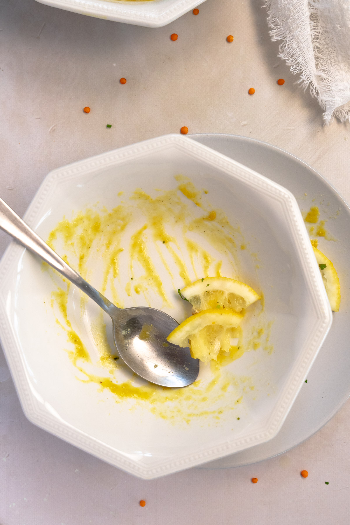 an empty bowl of lentil soup with leftover lemon pieces