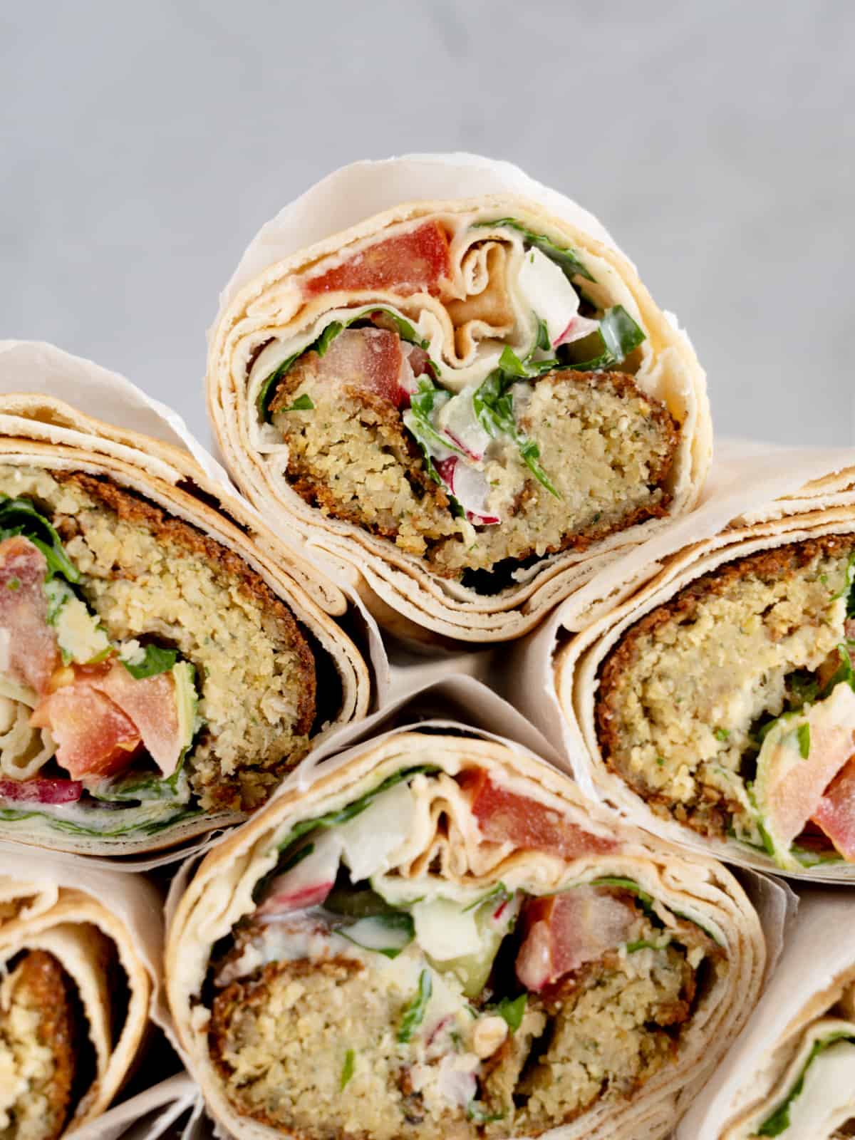 a stack of pita sandwich rolls filled with falafel and veggies