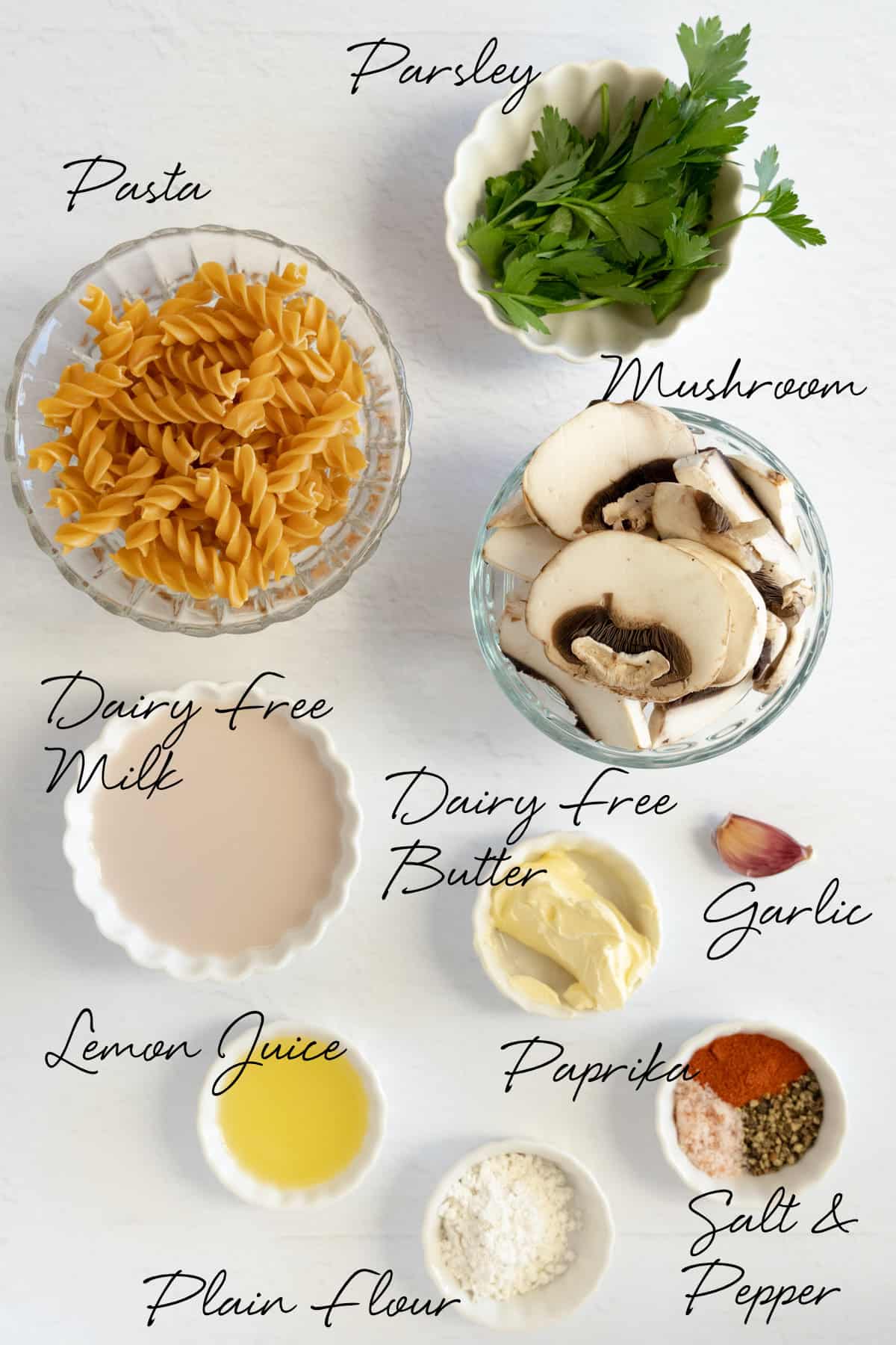 pasta, mushroom, parsley, milk, butter, garlic, lemon juice, salt, pepper, paprika and flour in white bowls