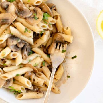a plate of penne pasta with mushroom sauce and a fork