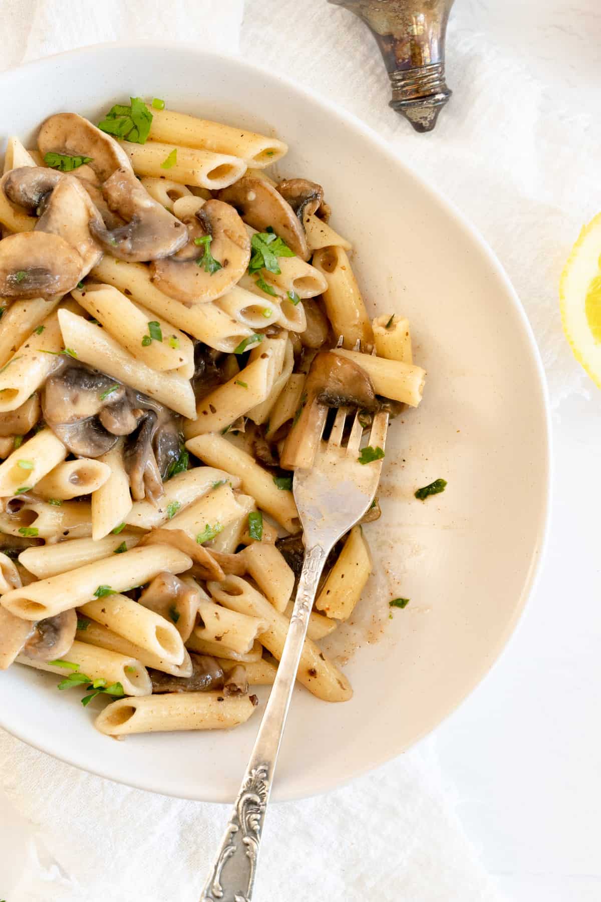a white bowl filled with mushroom and penne pasta