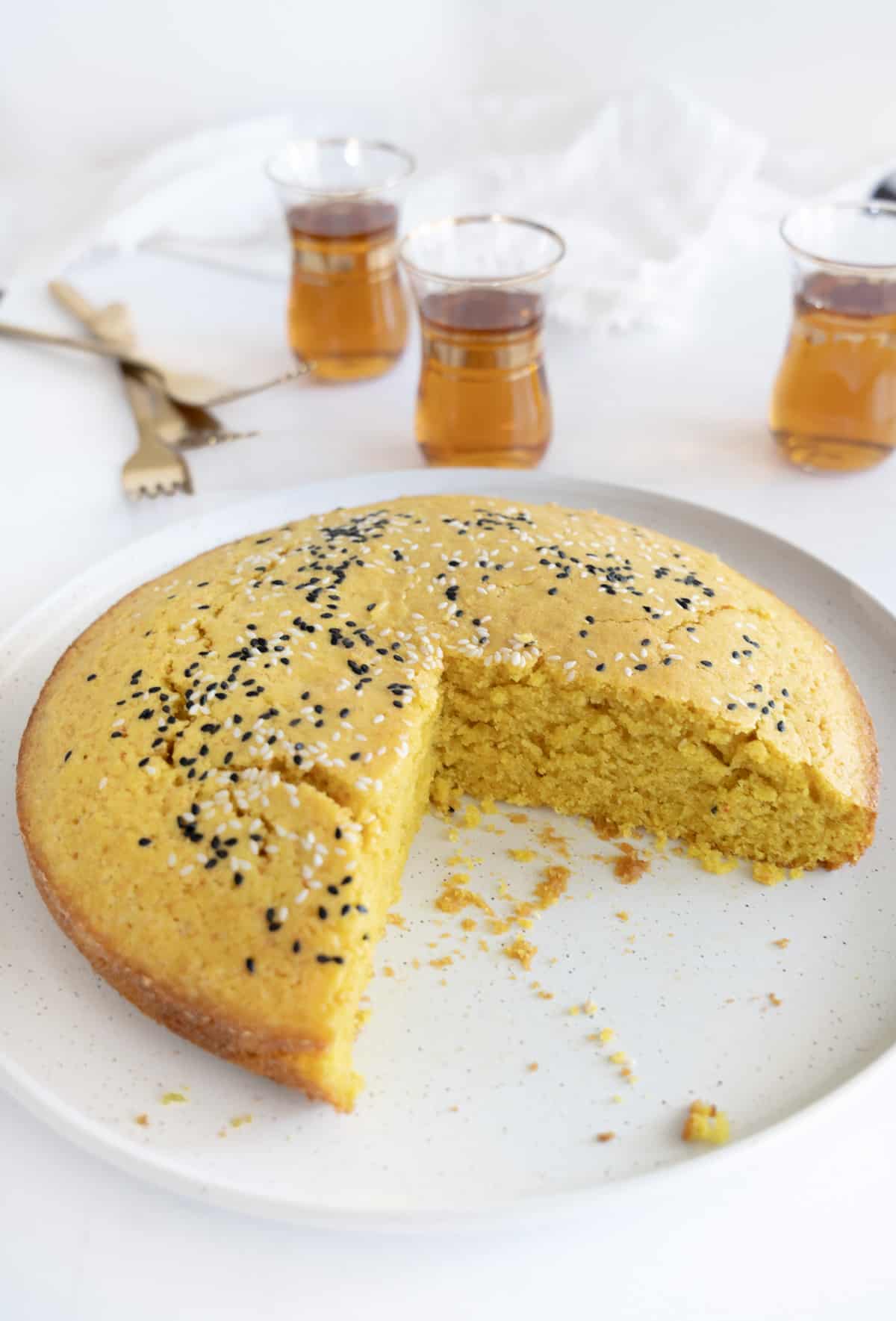 a round yellow turmeric semolina cake with a slice missing from it