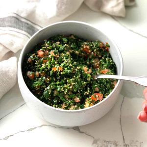 a white bowl of parsley, tomato and chopped quinoa