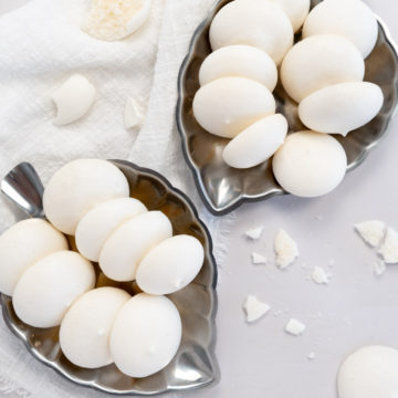 two silver plates of white vegan meringues