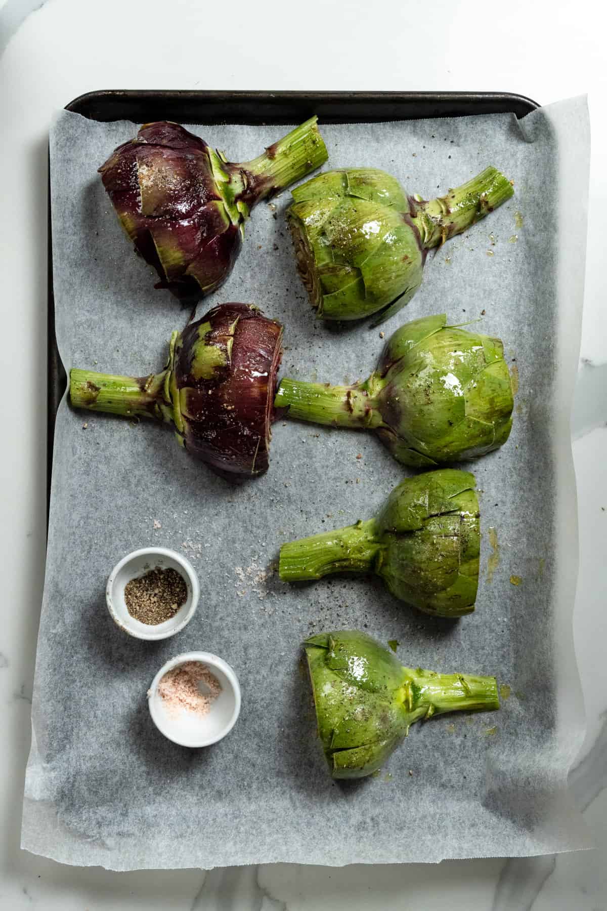 6 artichoke halves face down on a baking tray