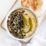a bowl of baba ganoush with pita bread on the side