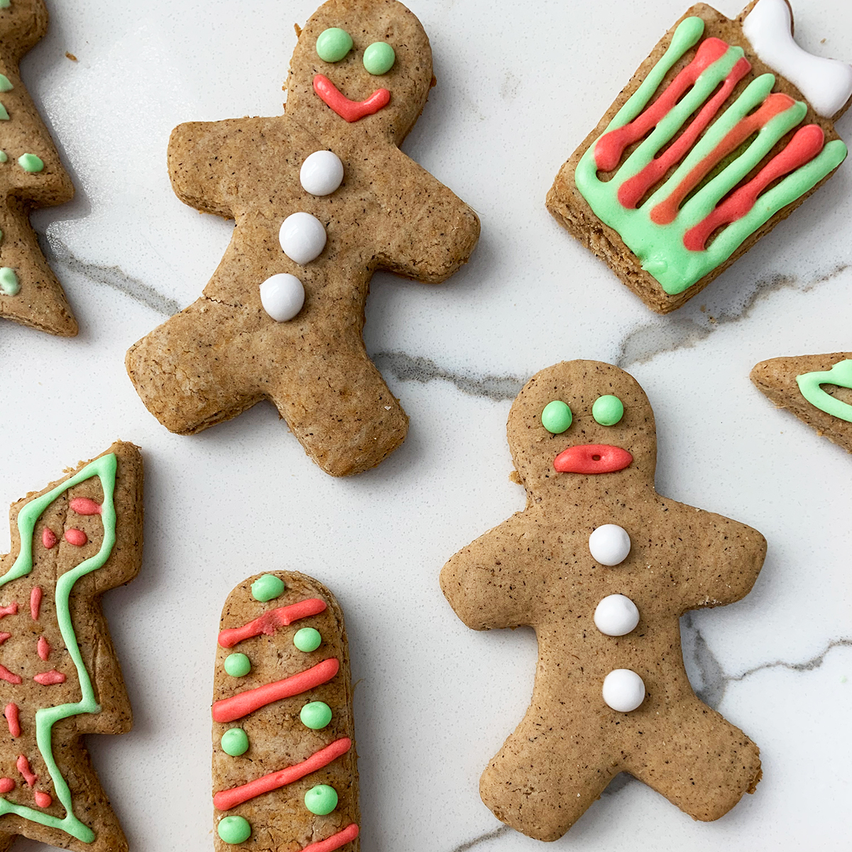 Christmas cookies in green, white and red icing on a white bench