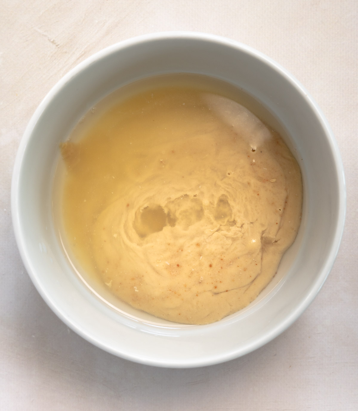 tahini, lemon, water and salt in a white bowl