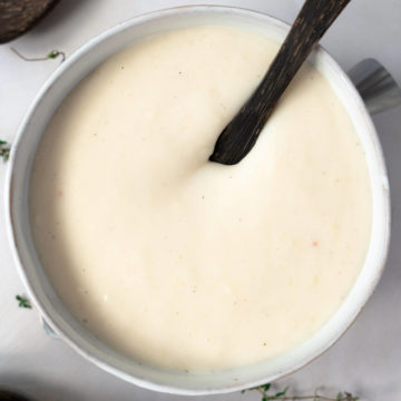 a white bowl with wooden spoon dipped into bechamel sauce