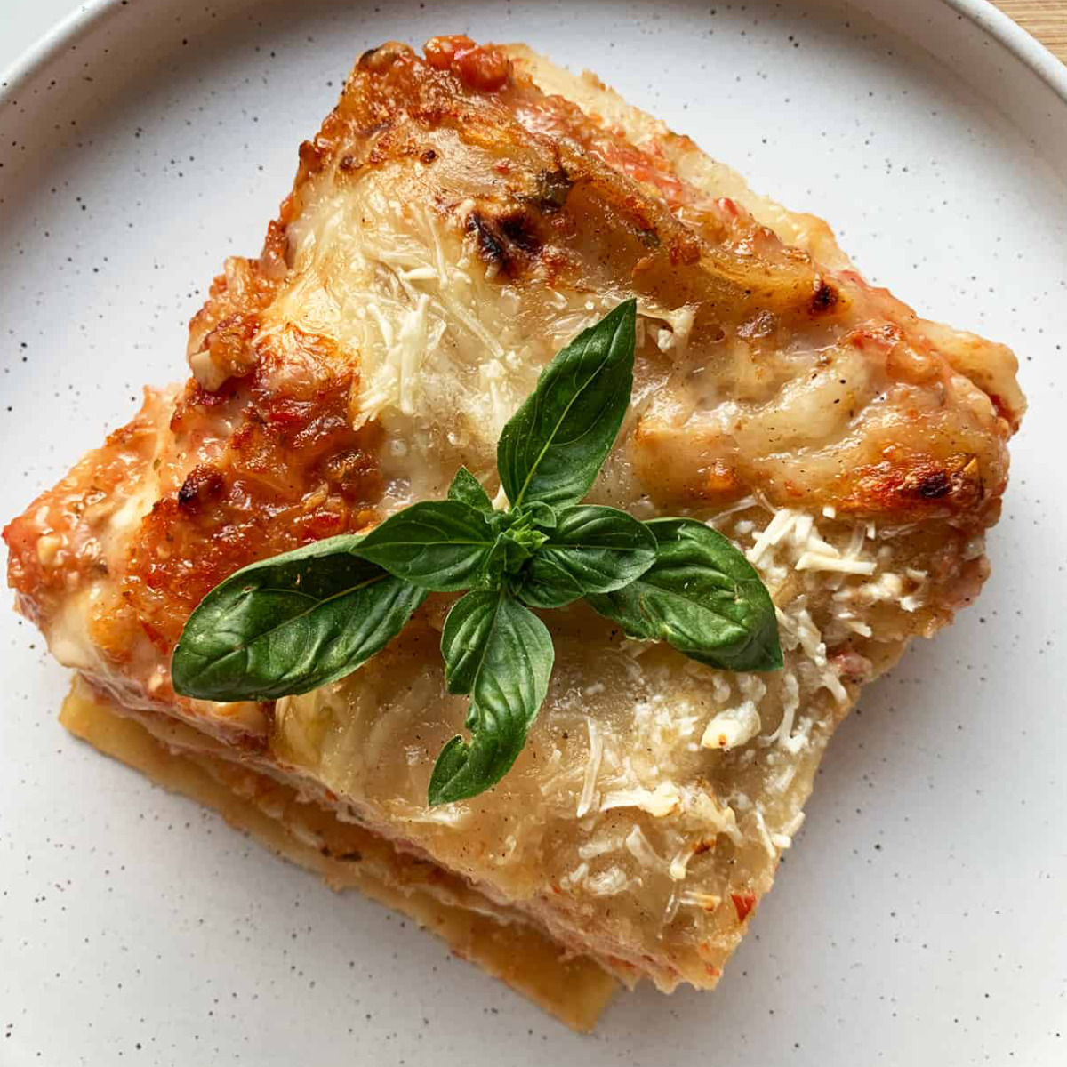 a piece of lasagna topped with fresh green basil