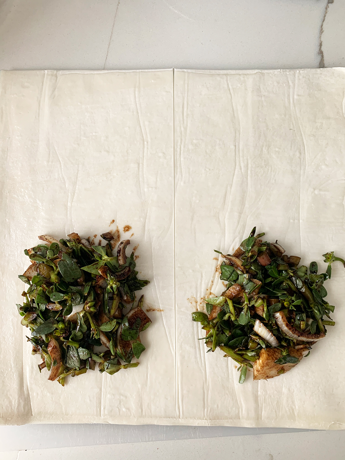 Purslane/bakleh filling placed on one edge of puff pastry sheet