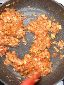 frying tomatoes and onion in a fry pan