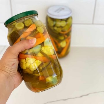 a hand hold a jar of pickled vegetables