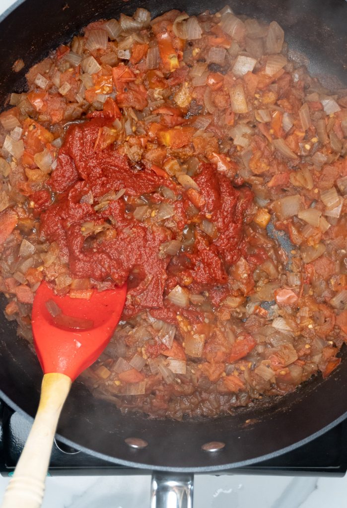 adding tomato paste to softened tomatoes and onion