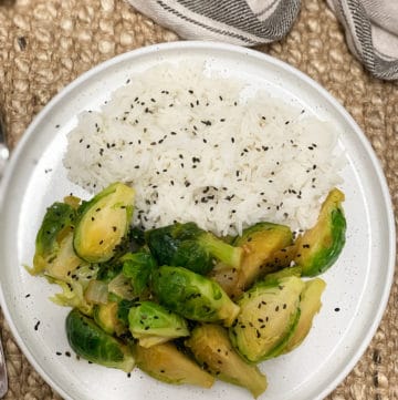 Brussels sprouts sauteed in garlic and soy served with rice and garnished with black sesame seeds