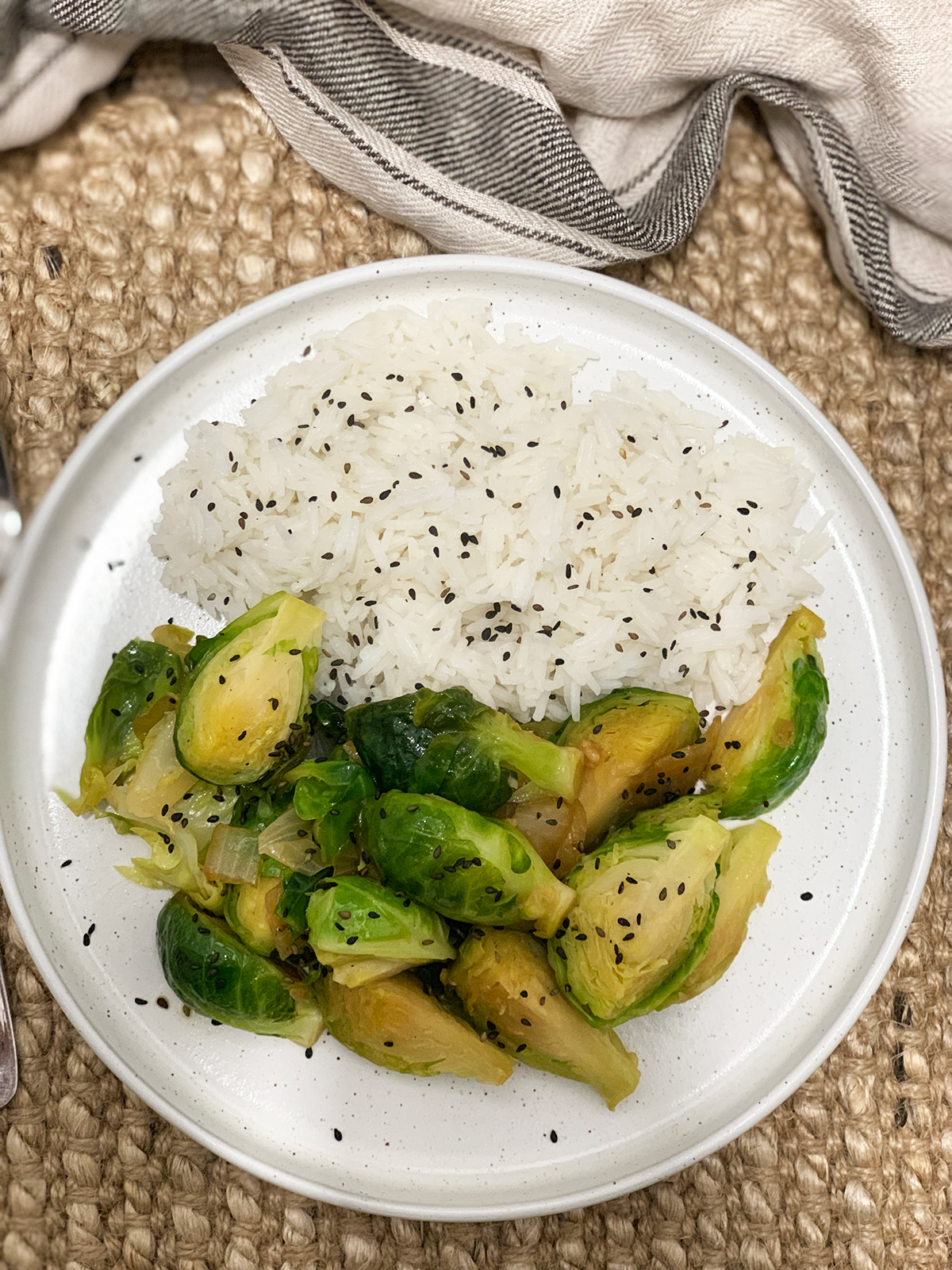 Brussels sprouts sauteed in garlic and soy served with rice and garnished with black sesame seeds