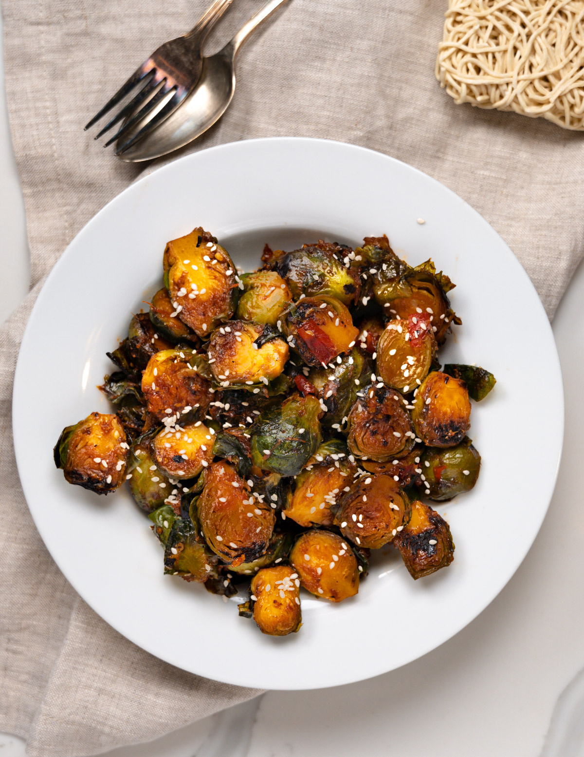 a plate of reddish brussels sprouts with cutlery on the side