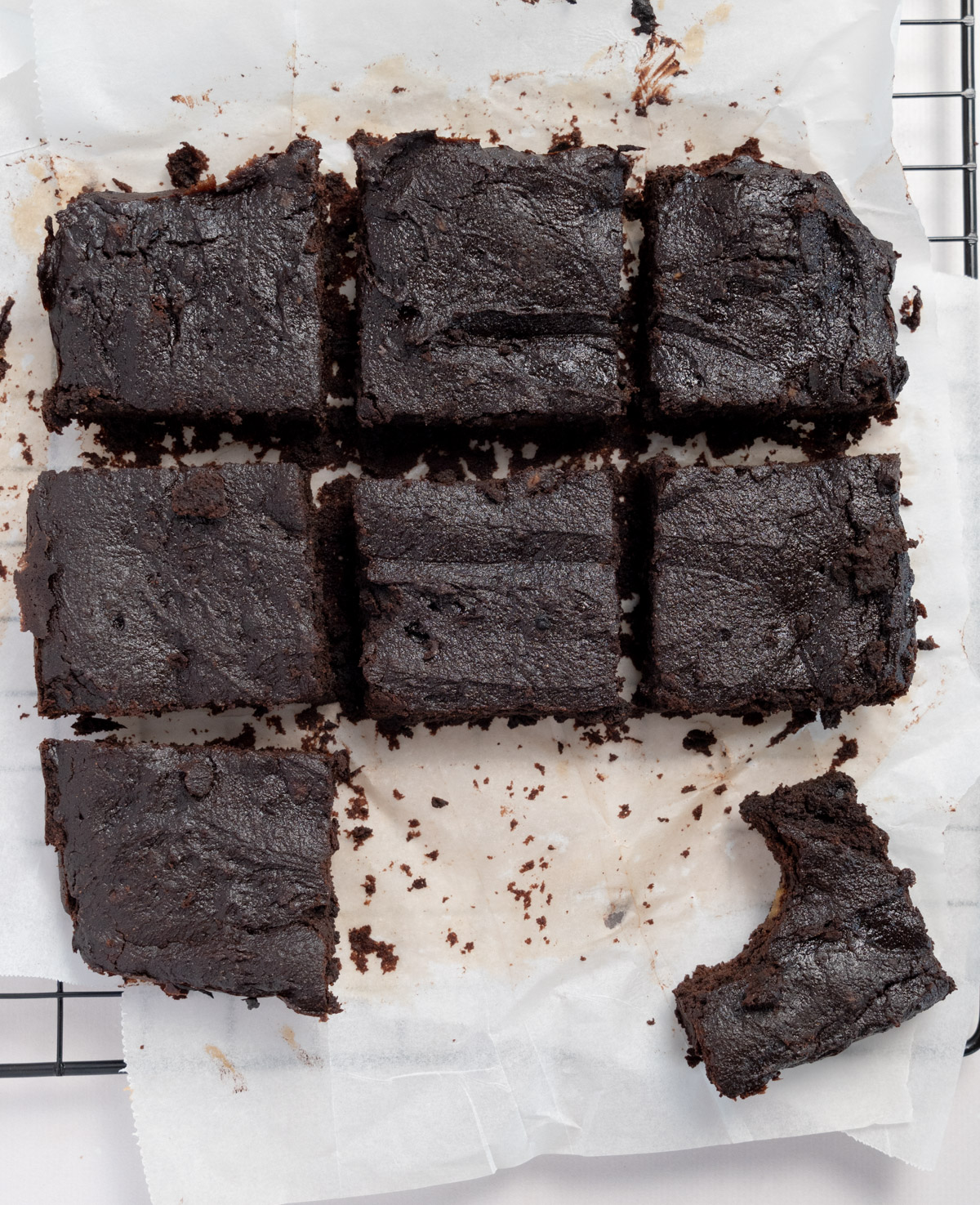 8 squares of brownies laid on baking paper, one with a bite out of it