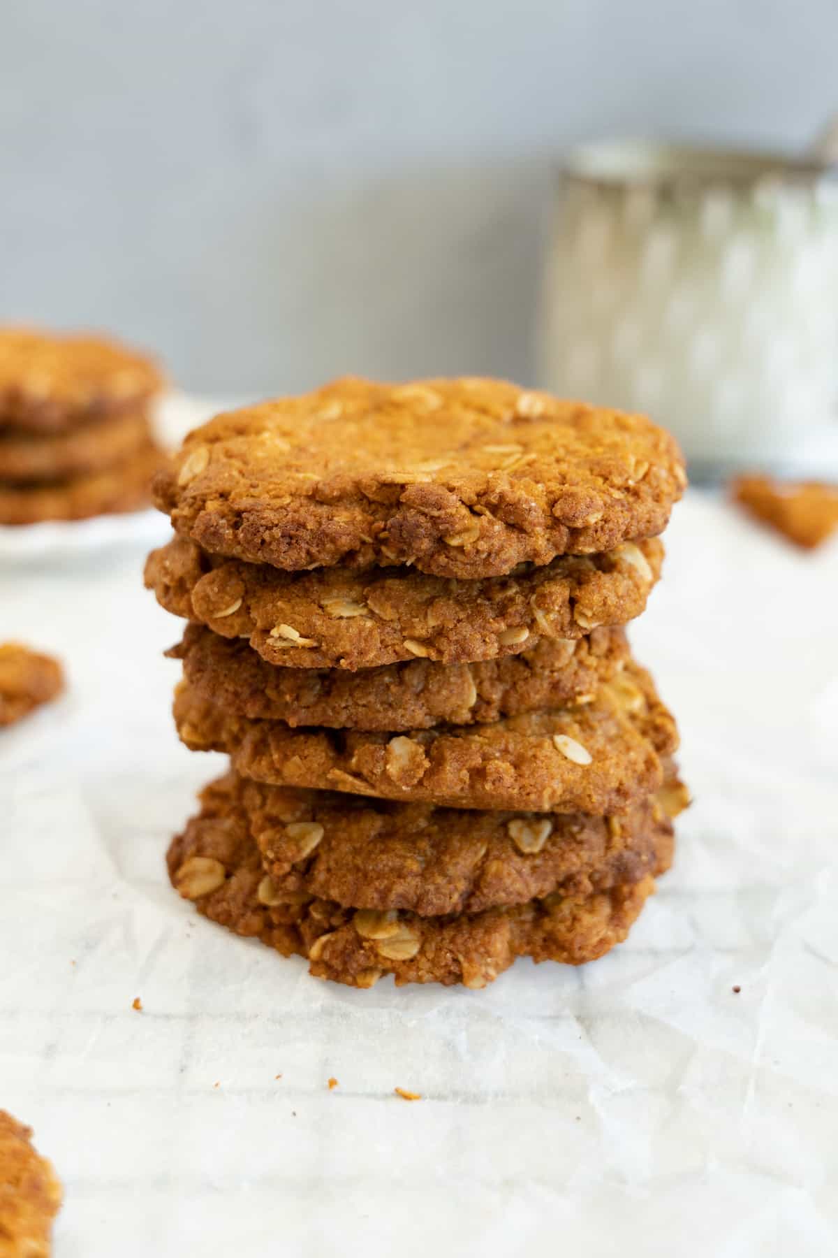a stack of 6 ANZAC biscuits with a green mug in the background