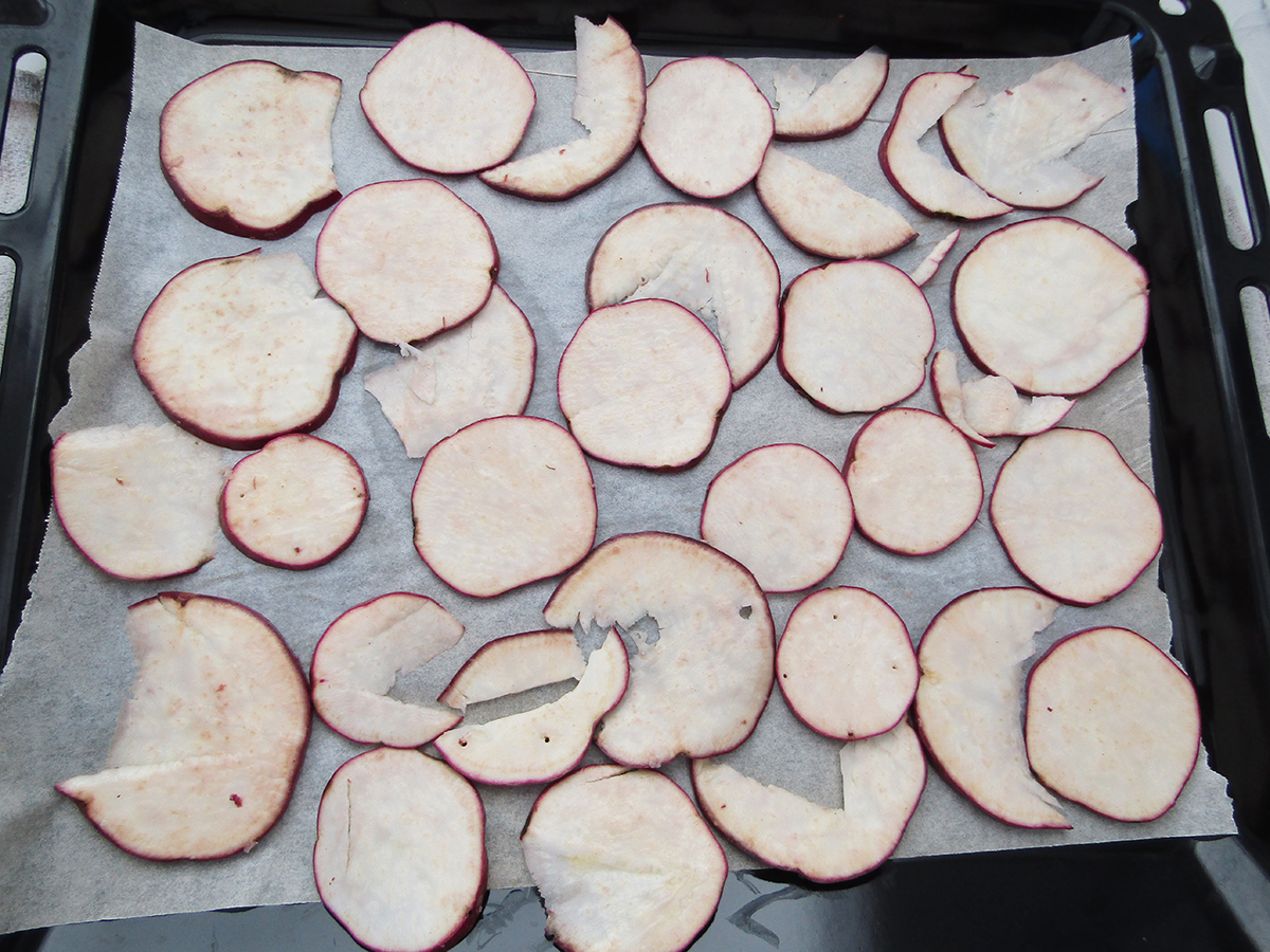 sliced up sweet potato on a lined baking tray