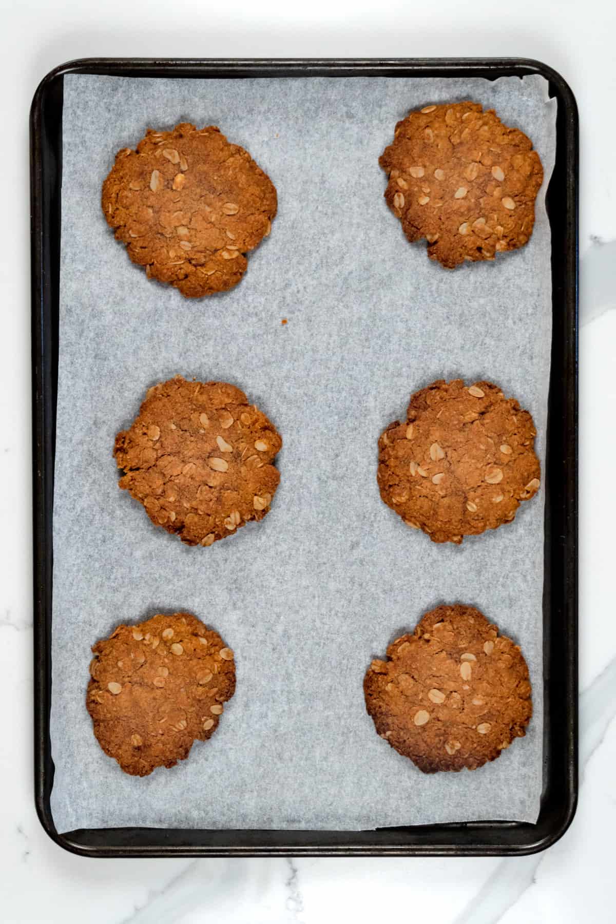 baked ANZAC biscuits in a paper lined tray