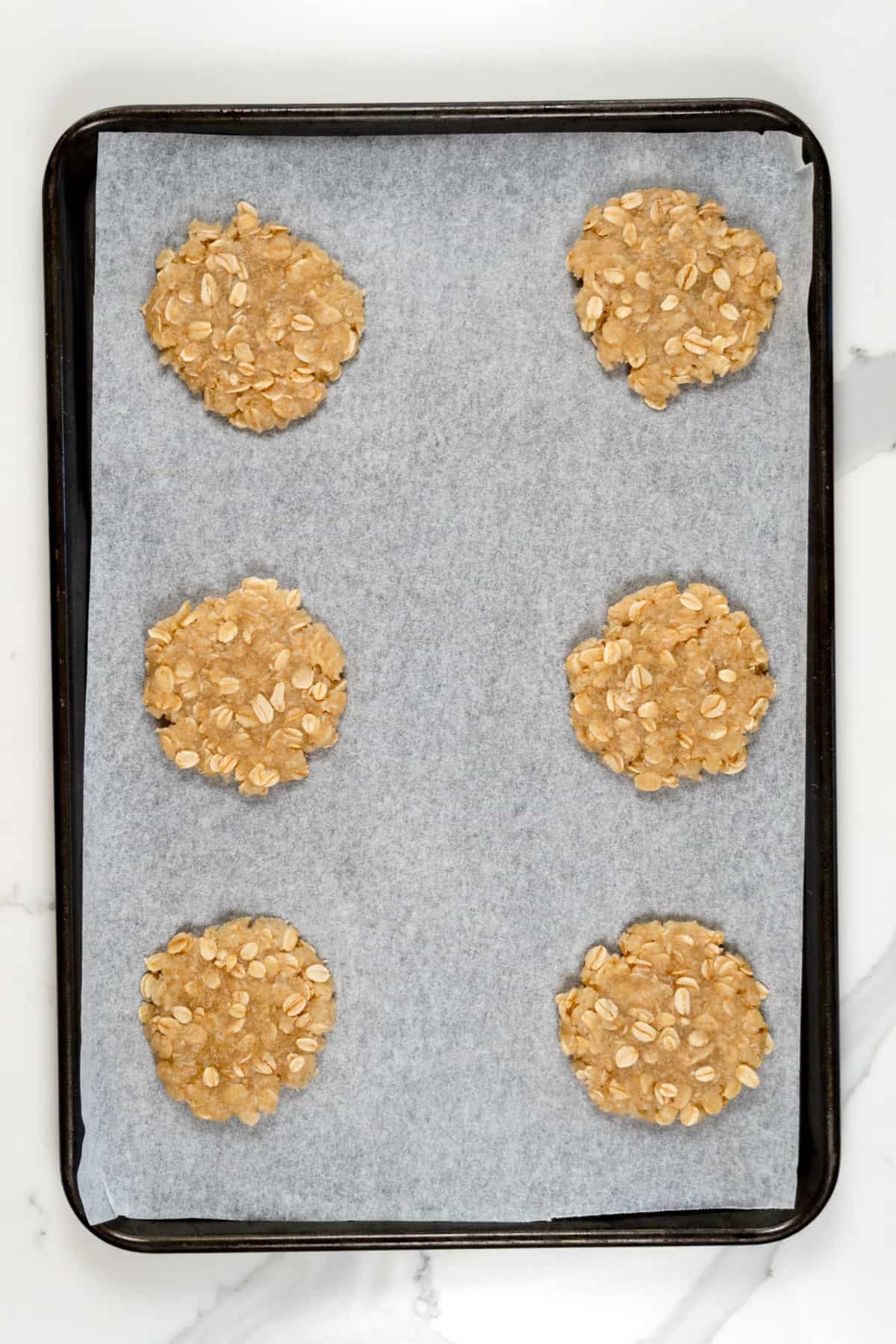 raw ANZAC biscuits in a paper lined tray