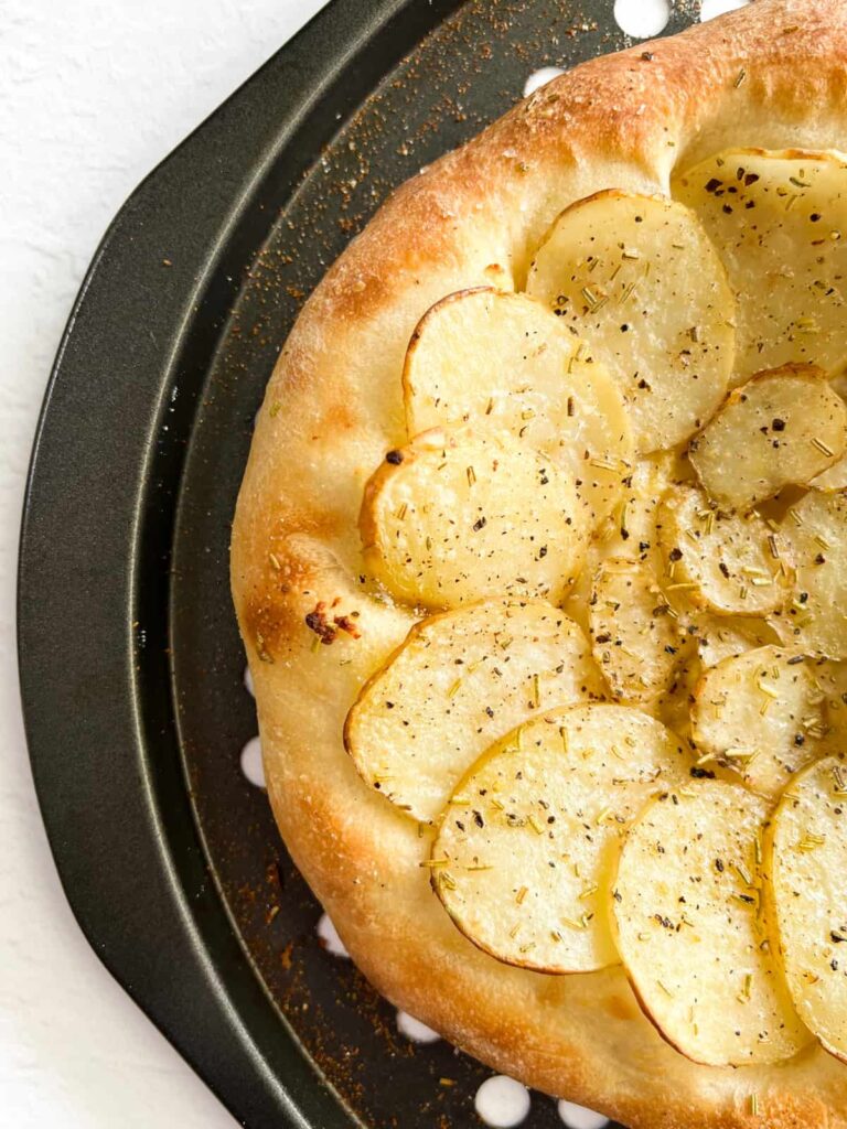a potato pizza in a grey pizza pan