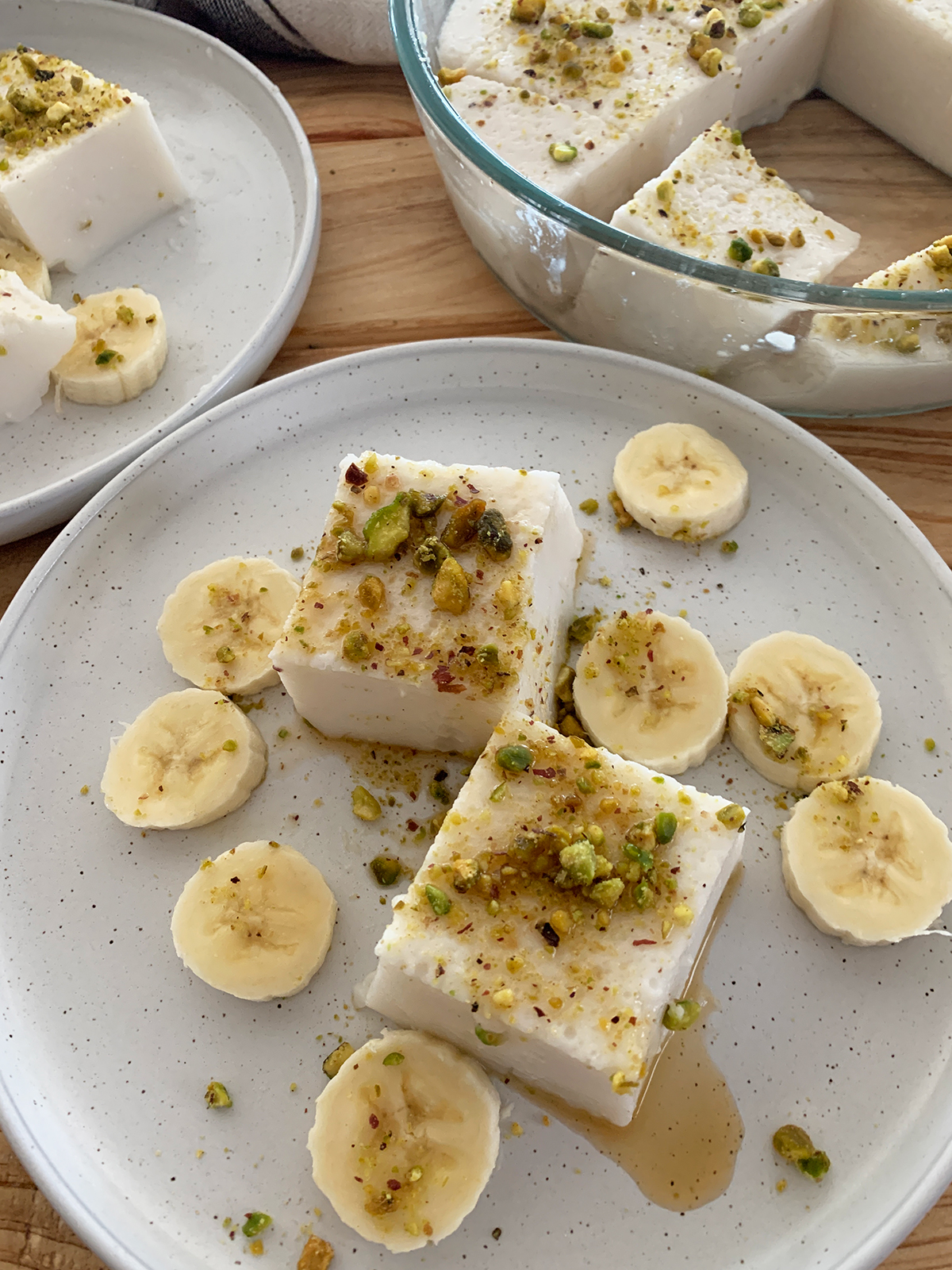 Haytaliyeh served in cubes on a white plate with banana and the original tray in the backgroud