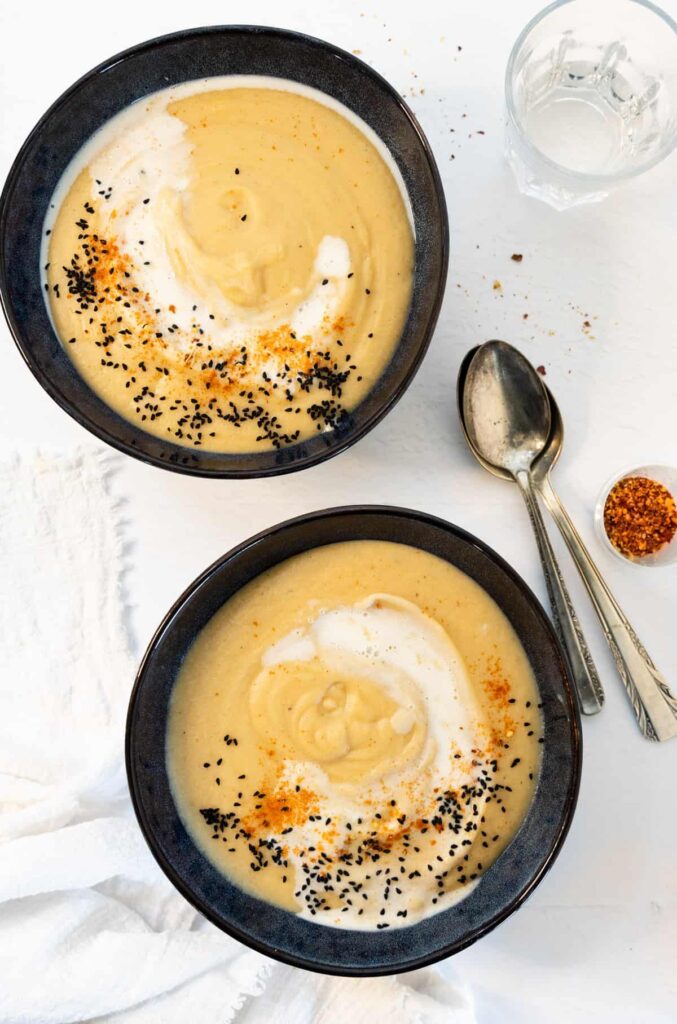 two navy bowls with yellow cauliflower soup