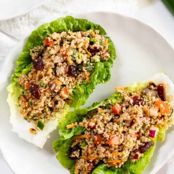 a white plate with two pieces of lettuce filled with colourful couscous salad