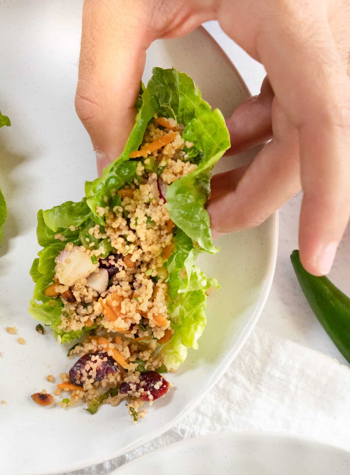 a male hand holding a lettuce cup with salad