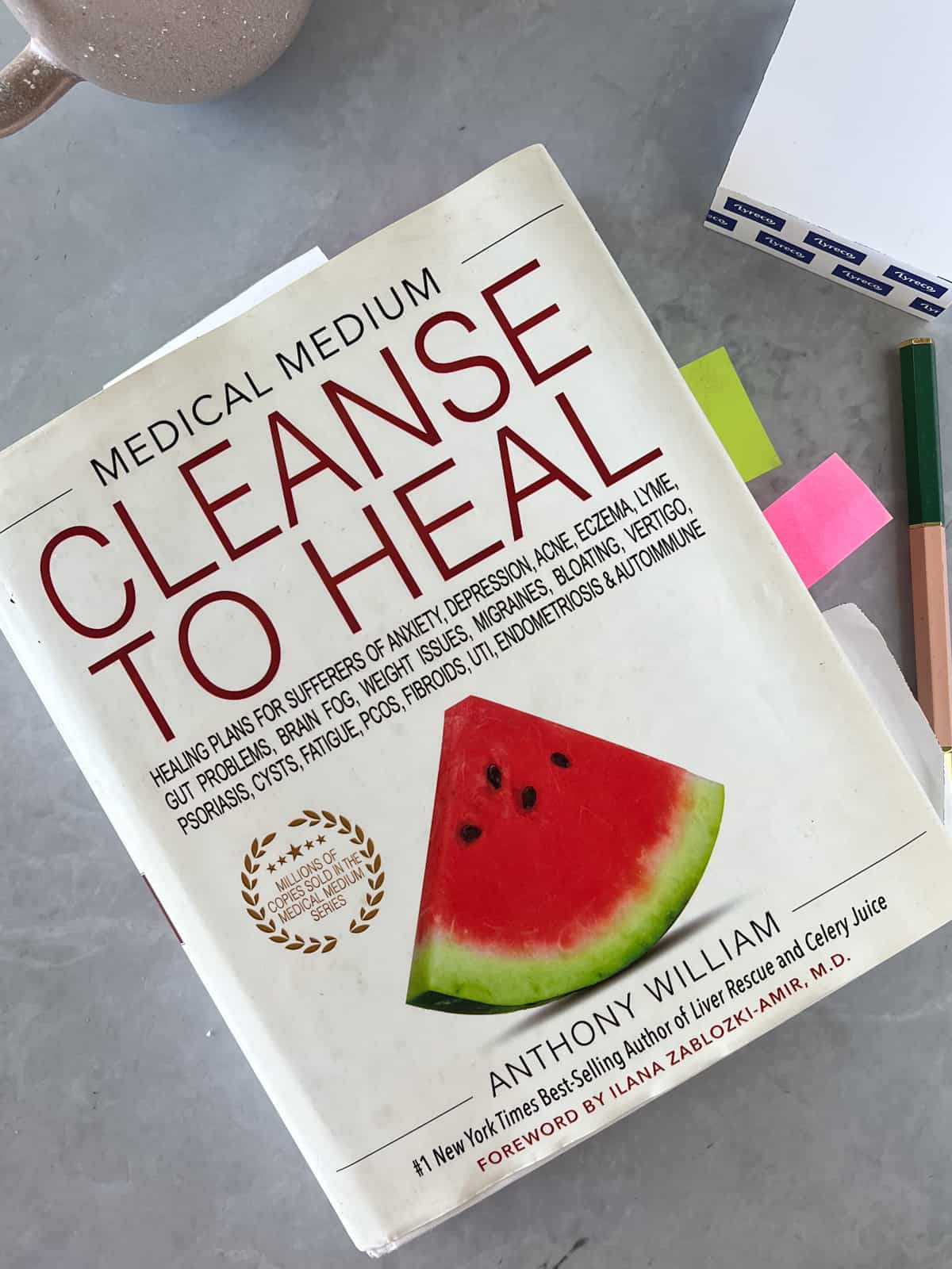 a white book with title cleanse to heal with a piece of watermelon on it