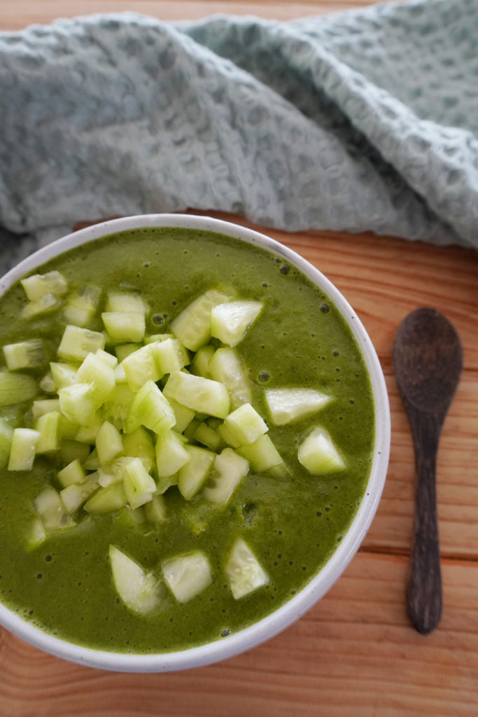 Raw spinach soup topped with pieces of cucumber