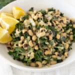 cooked black eyed peas with greens in a white bowl