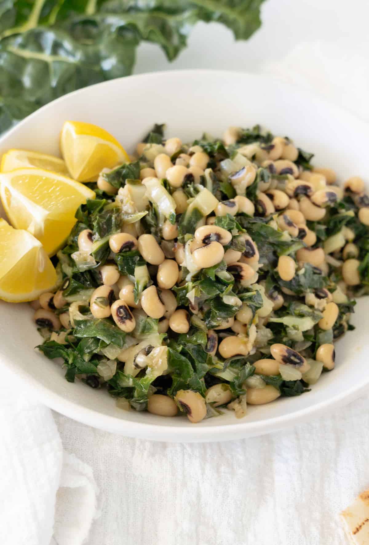 cooked black eyed peas with greens in a white bowl