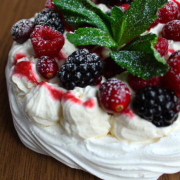 vegan pavlova covered in berries and mint garnish
