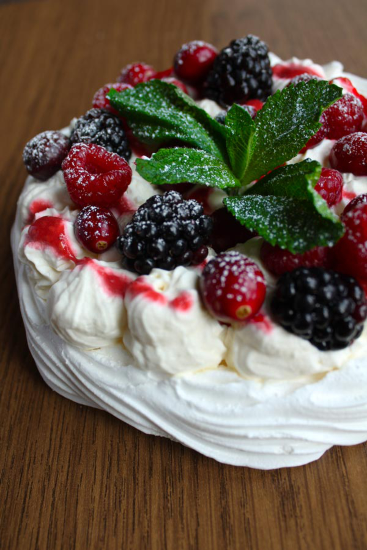 vegan pavlova covered in berries and mint garnish