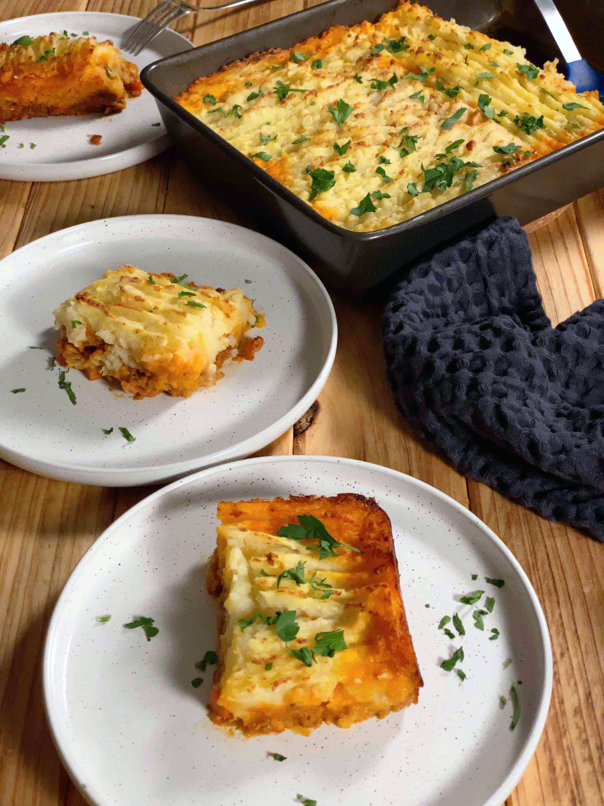 two white plates with a slice of vegan shepherd's pie