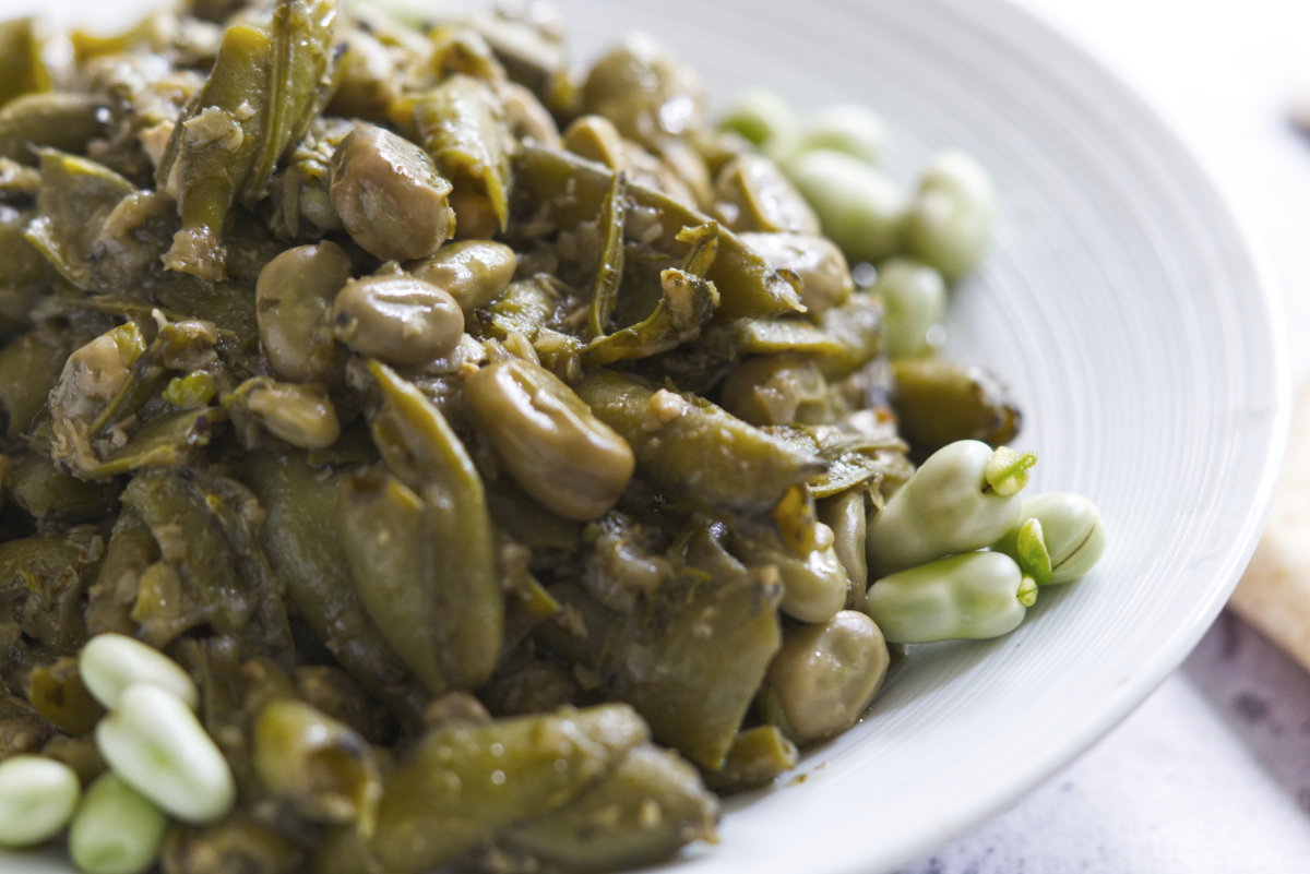 green broad beans in olive oil in a white plate
