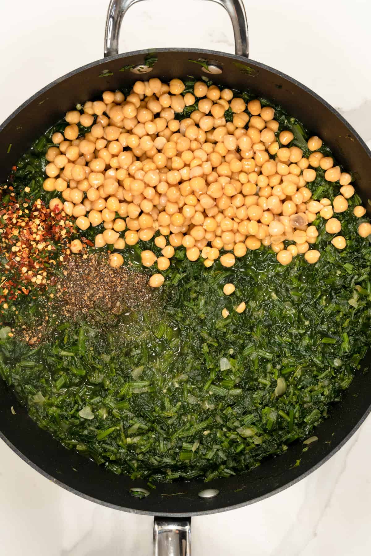 wilted spinach with chickpeas and seasoning in a pot