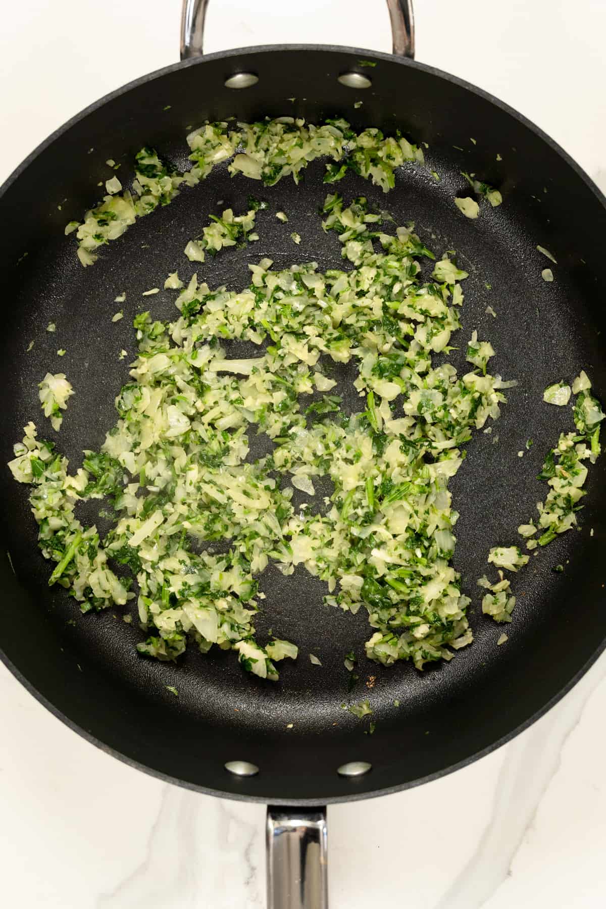 black pot with diced onion, crushed garlic and chopped cilantro