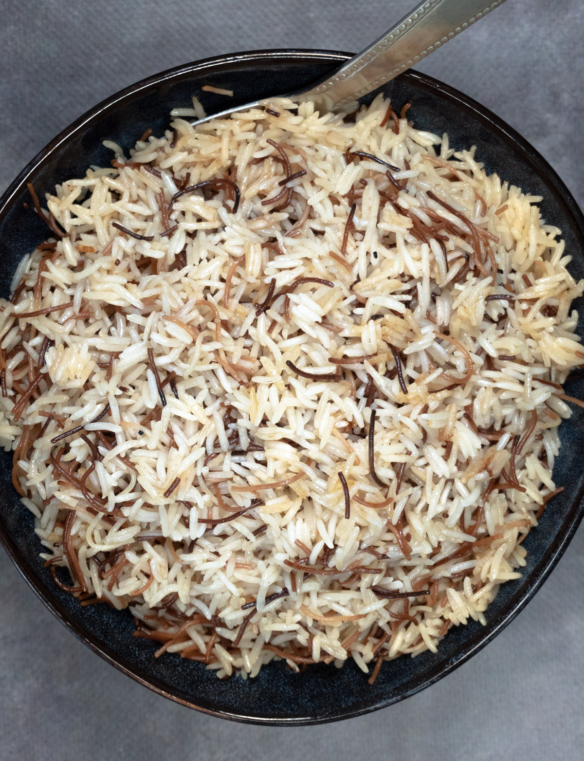 a navy bowl of rice with vermicelli through it