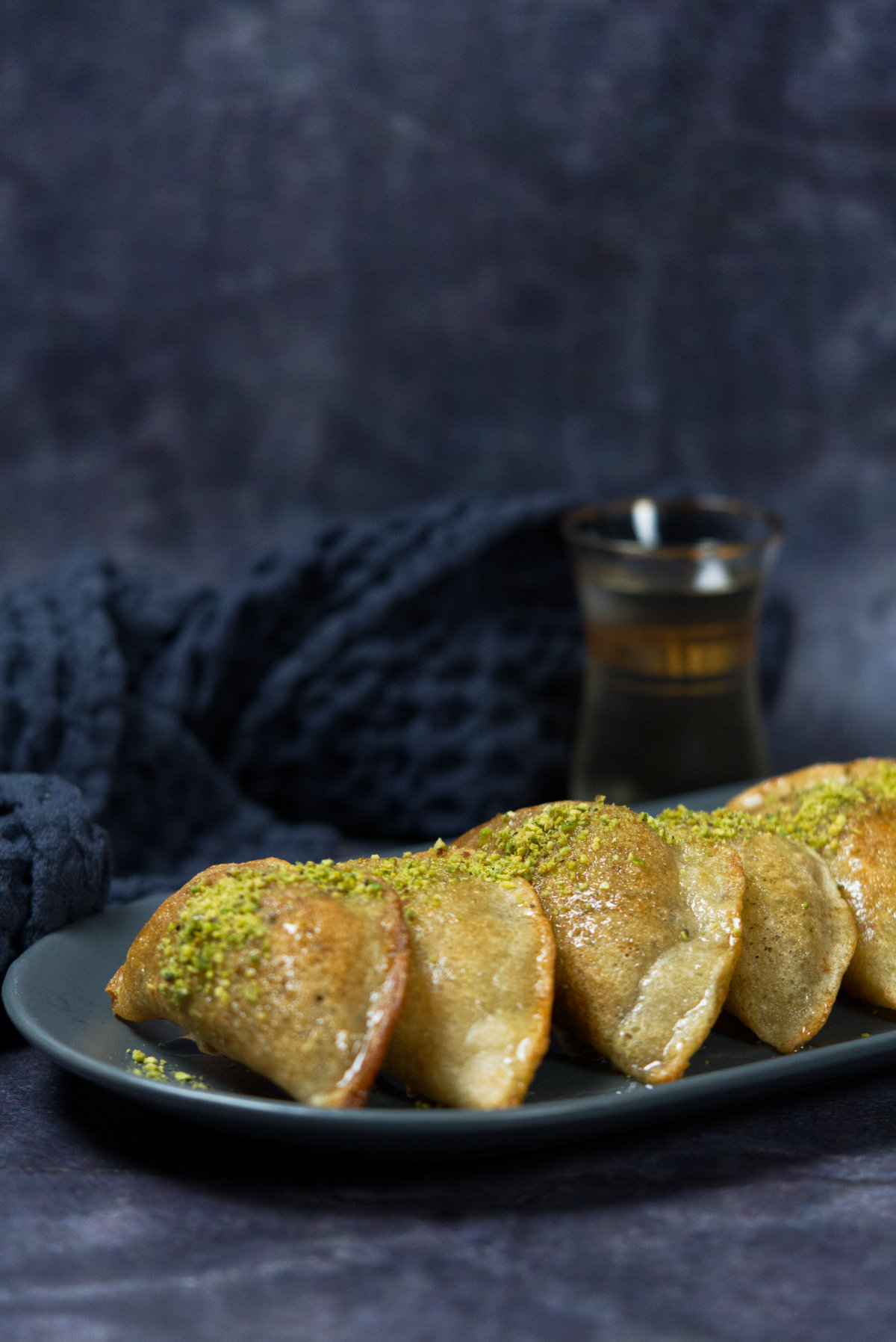 Baked atayef in a plate with an arabian tea in the background