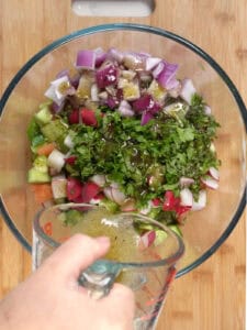 mixing fattoush chopped veggies with salad dressing
