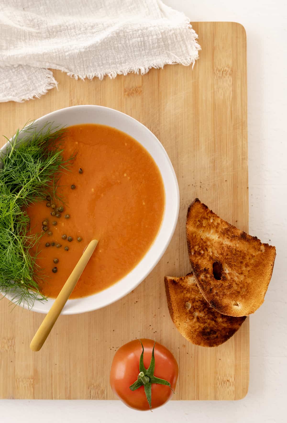 a bowl of tomato fennel soup with toasted bread sliced next to it