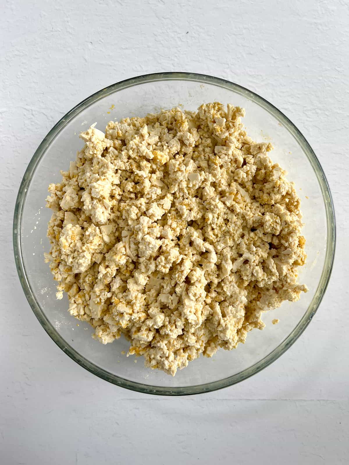 crumbled tofu with yellow seasoning on it in a glass bowl