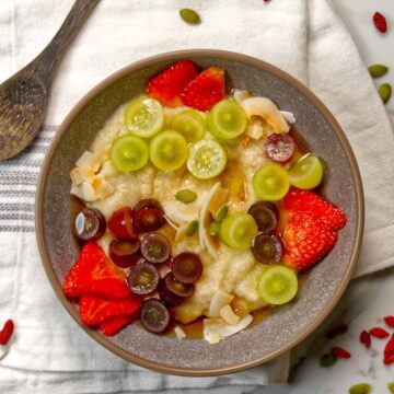 grey bowl with quinoa porridge topped with fresh fruit
